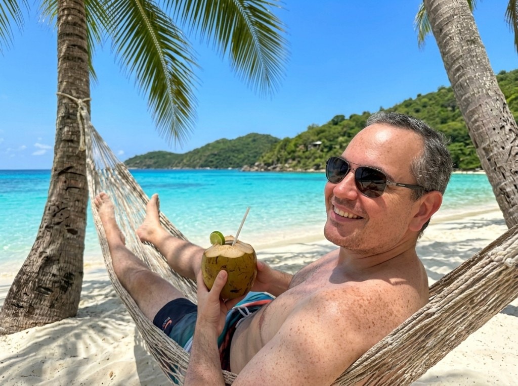 Smiling person in a hammock on a tropical beach with turquoise water
